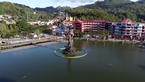 aerial view of a large statue in a lake, surrounded by a town and mountains