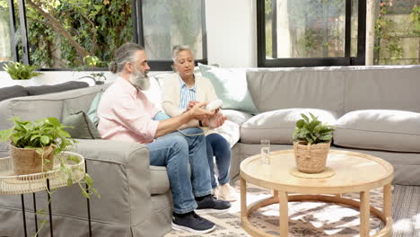senior couple sitting on sofa, examining medication bottle in living room