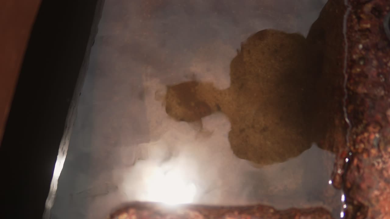 한 여자의 반사 (反射) 가 은 물 속에 나타나며, 날씨가 변한 돌 에 빛과 물, 그리고 고대 요소들 사이의 상호 작용을 강조합니다.