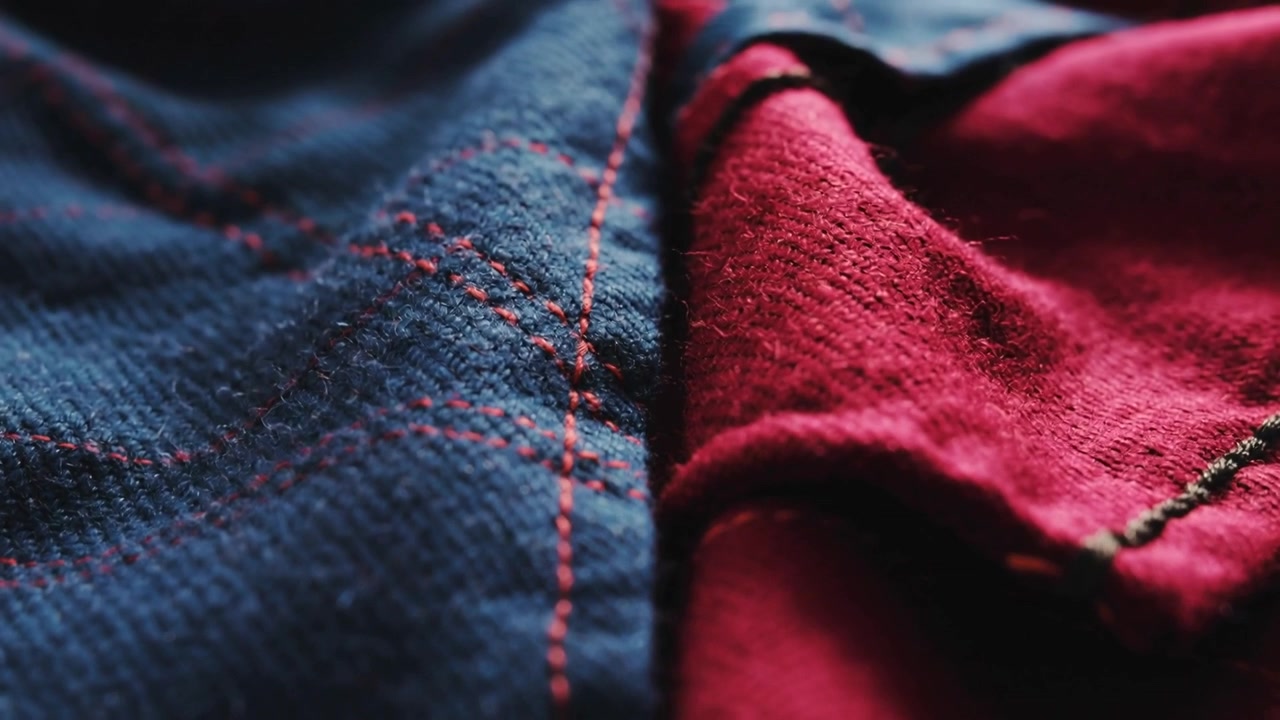 Focusing camera shifting over blue textile and red folded fabric on table, showing stitch detail