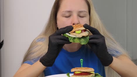 una mujer comiendo una hamburguesa.