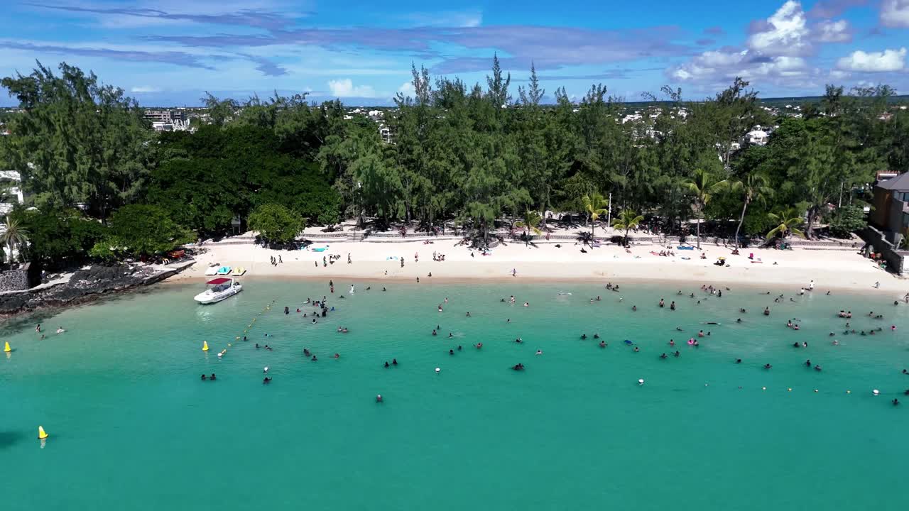 Aerial view of Pereybere Beach, Mauritius with swimmers in turquoise water, white sand, and lush trees. Perfect for tropical lifestyle, travel, tourism, or summer leisure concepts.