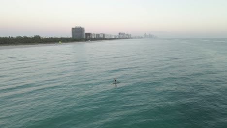 Orbiting-aerial-of-stand-up-ocean-paddleboarder-alone-off-Miami-Beach