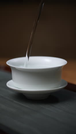 pouring tea into a white porcelain tea bowl