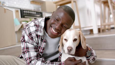 portrait of happy african american man sitting on stairs with his pet dog at home, slow motion