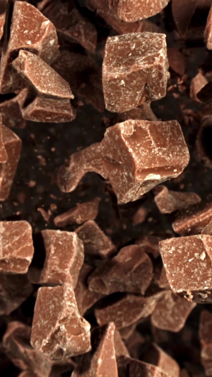 Movimento rallentato di pezzi di cioccolato che cadono su sfondo scuro