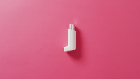 Video-of-close-up-of-white-inhaler-on-pink-background