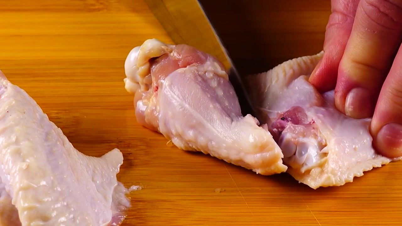 Le ali di pollo vengono tagliate con un coltello su un tagliere