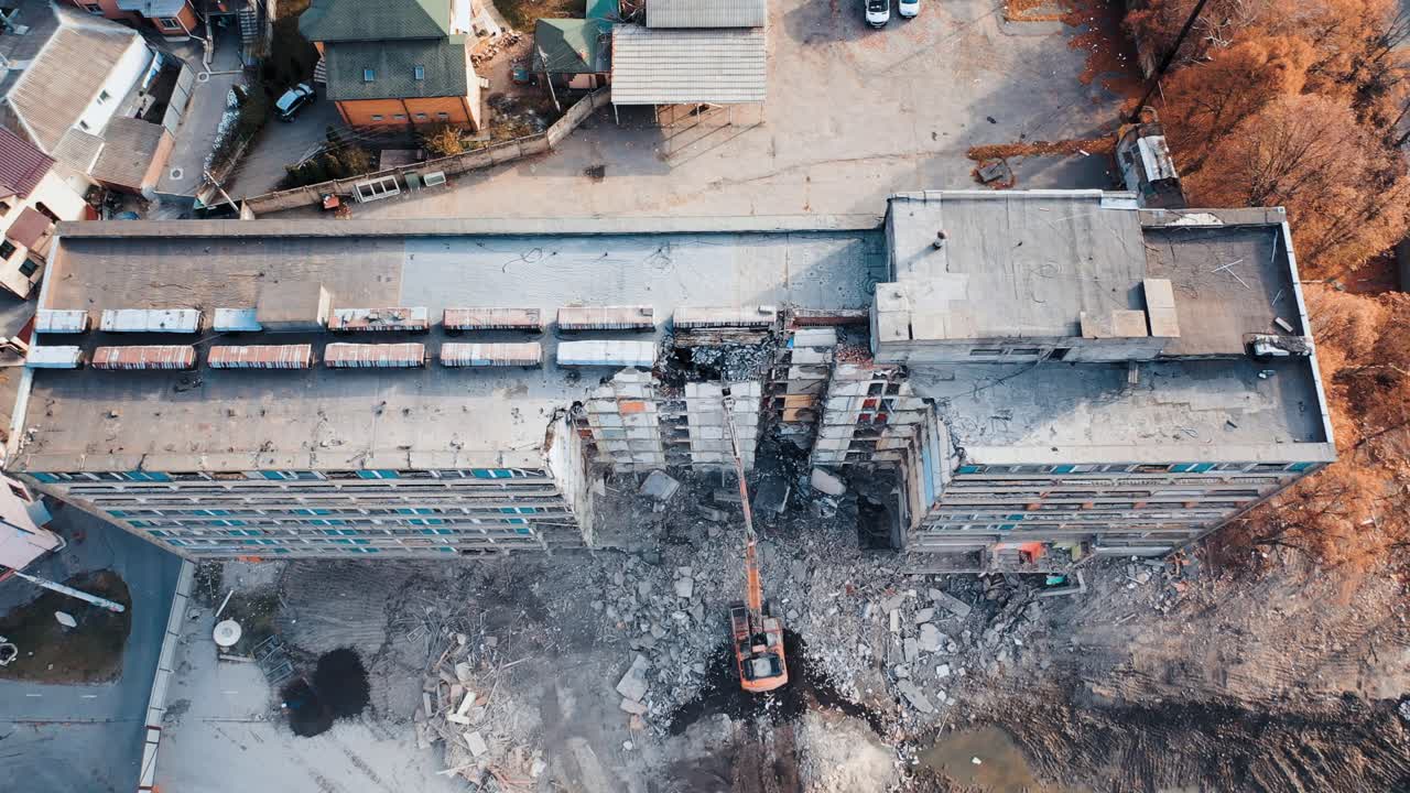 Natural disaster demolition building. Excavator at a construction site disassembles construction debris. Aerial view