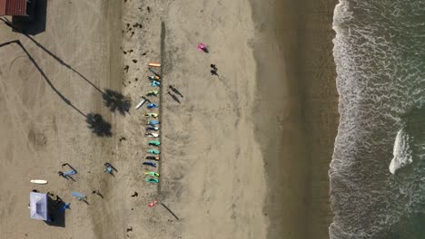 down facing drone view of a group of surfers in san diego waxing their surf boards