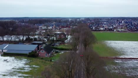 aerial view above car driving on road through farm fields in bergeijk, netherlands