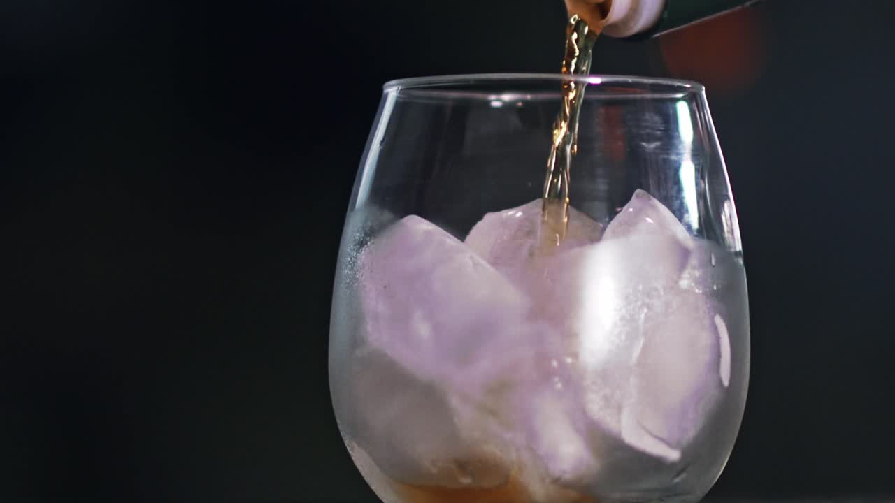 verter té helado refrescante de una botella en un vaso grande lleno de hielo