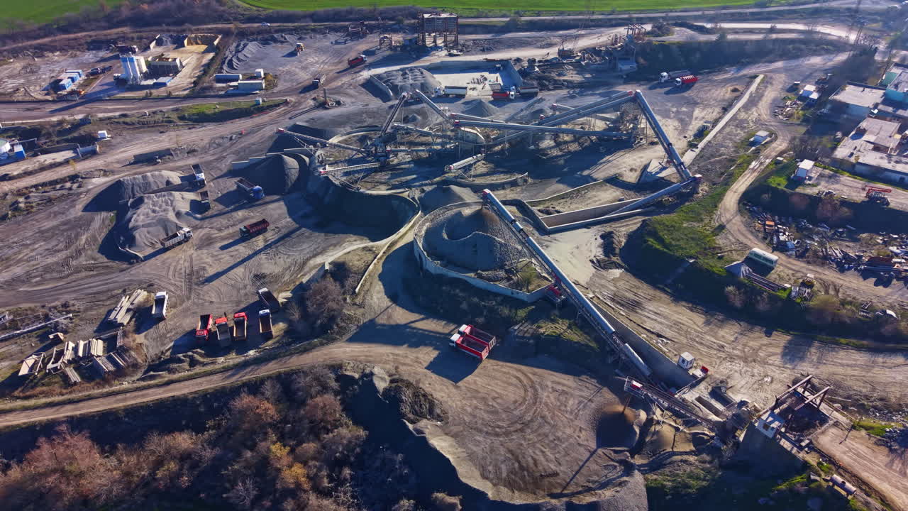 Excavation site bustling with heavy machinery among piles of gravel and earth during bright daylight