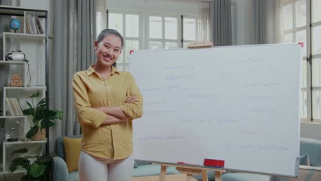 asian female teacher crossing arms and smiling to camera while teaching english at home