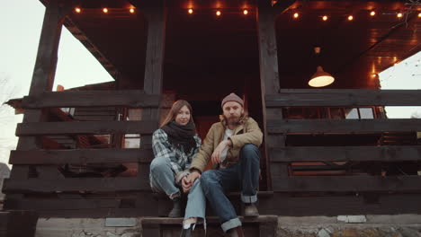 portrait of young couple sitting on stairs of wooden terrace