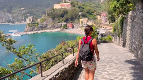young woman walking through picturesque streets of cinque terre, italy – rear view in colorful mediterranean village