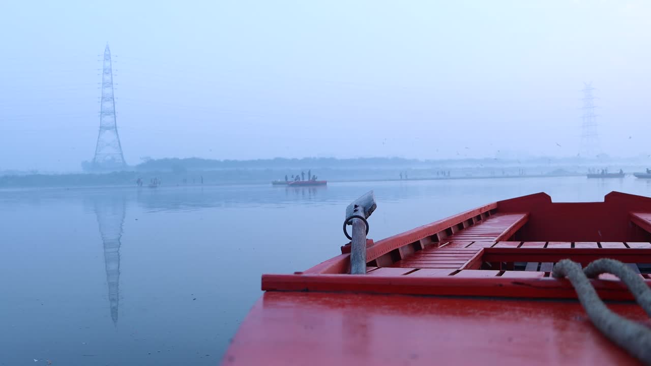 закрытый кадр лодки, пришвартованной на спокойном озере, с окружающей водой и небом, окутанным туманной, туманной погодой, создавая спокойную и атмосферную сцену тишины и спокойствия в индии