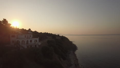 Vista-Aérea-De-La-Carretera-Costera-Y-El-Paisaje-De-Las-Tierras-Altas-Al-Atardecer-En-Grecia