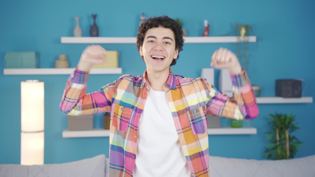 유쾌한 십대 남성이 기 ⁇ 하고, 카메라를 쳐다보고 미소 짓습니다.