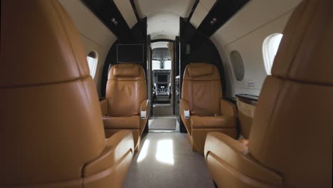 brown leather seats in cabin of luxury private aircraft facing flight deck