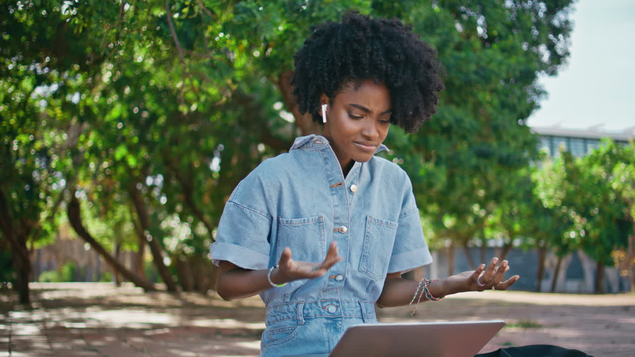 Businesswoman talking video meeting by laptop sitting sunny park closeup