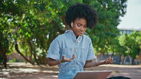 mujer de negocios hablando reunión de video por computadora portátil sentada en el parque soleado de primer plano