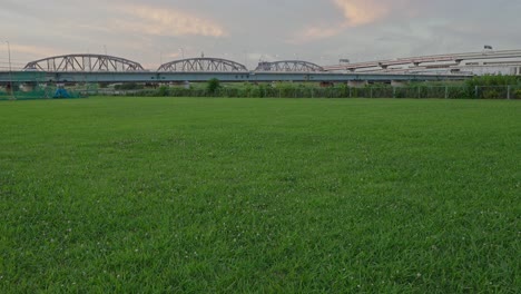 a wide, low-angle shot of a lush green field with the horikiri bridge in the background