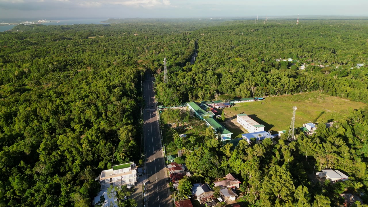 Scenic aerial view of provincial highway road at lush barangay village, Jordan, with forest canopy - Guimaras, Philippines