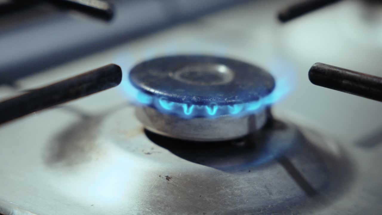 Close-up of a gas stove burner with a blue flame, symbolizing cooking, warmth, and energy, with a dominant blue hue