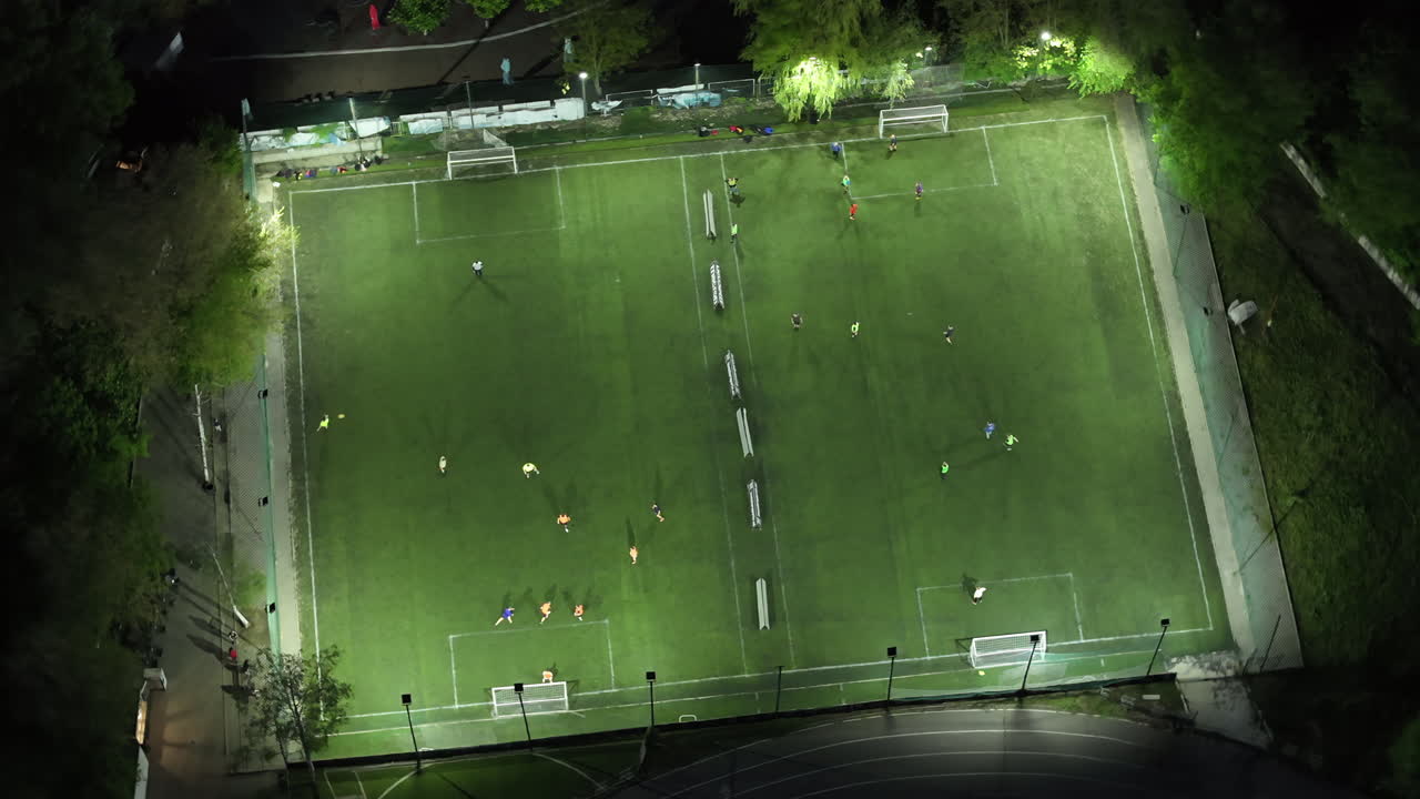 People playing football on two illuminated stadiums at night