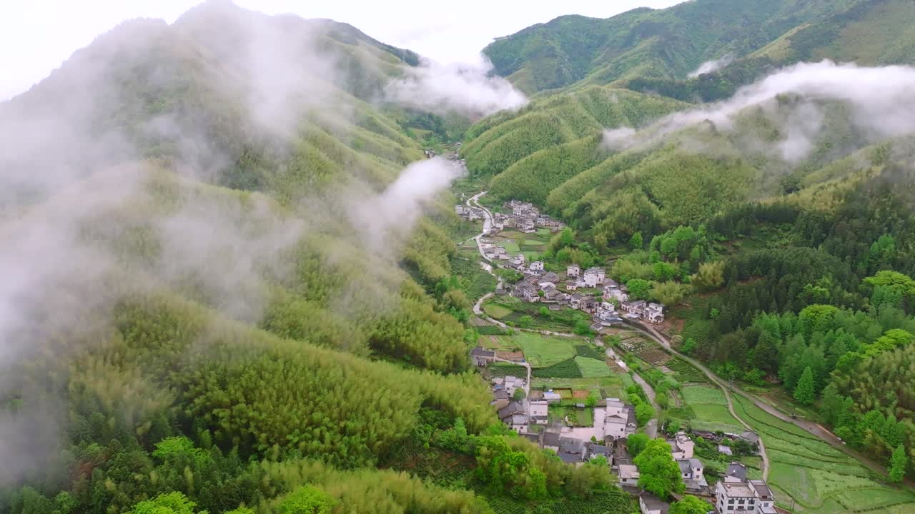 Aerial photography of high mountains shrouded in clouds and mist after rain, humid climate, and green forests shrouded in mist