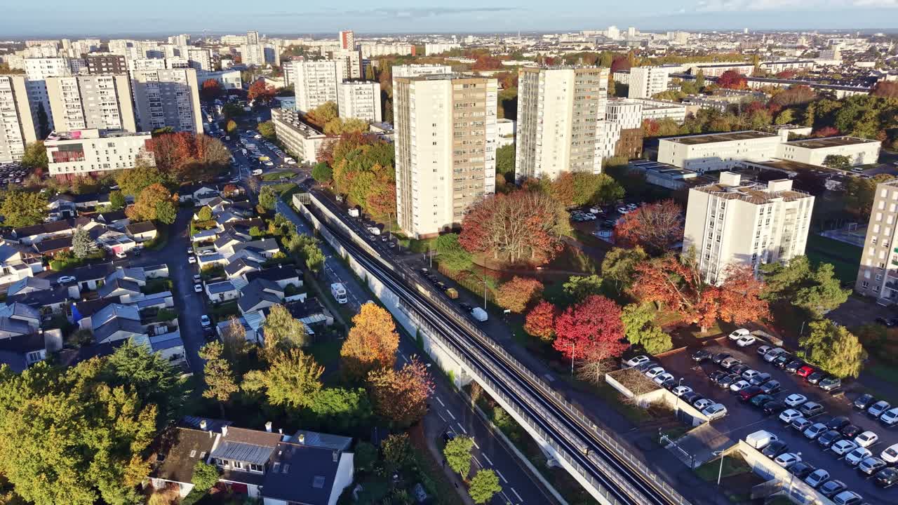 Panorama drone view of apartment buildings with parked cars along 'La Poterie' metro traffic in autumn foliage, Rennes, Brittany, France