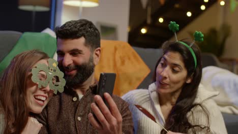 grupo de amigos disfrazándose en casa celebrando en la fiesta del día de san patricio haciendo una llamada de video en el teléfono móvil