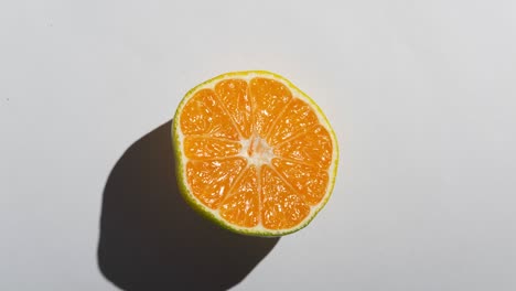 mitades de mandarina frescas con una fuerte sombra en un fondo blanco. animación de comida en stop motion