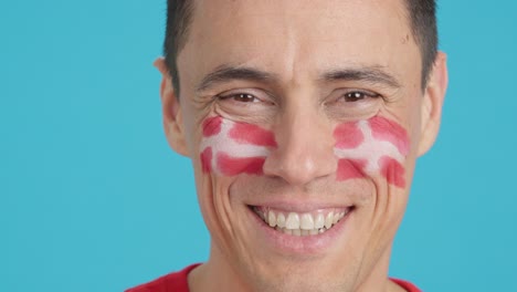 man with a danish flag painted on the face smiling