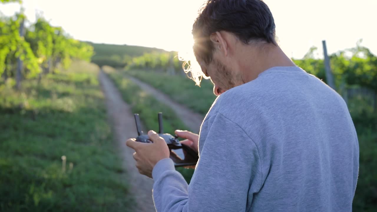 hombre operando drone con control remoto al aire libre al atardecer, plano medio
