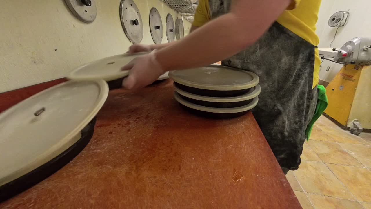 Worker organizing cast iron pans of pizza.