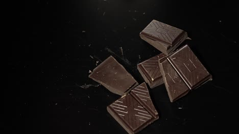 woman breaks black chocolate bar. close-up. slow motion