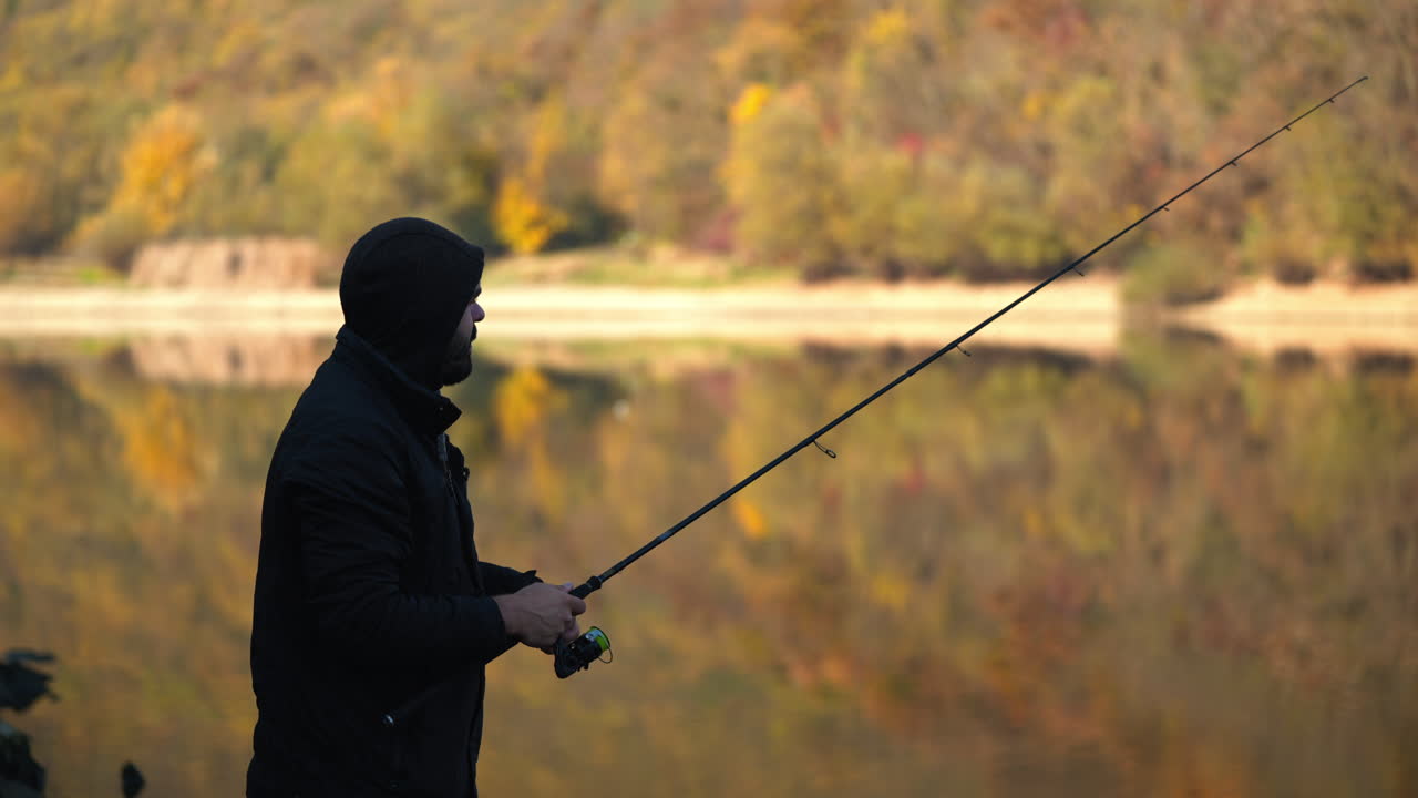Seorang pemancing menikmati hari memancing di danau yang tenang di musim gugur