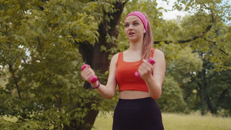 Chica-Atlética-Joven-En-Forma-Deportiva-Haciendo-Ejercicios-Con-Pesas-En-El-Parque-Soleado-Realizando-Ejercicio-De-Bíceps