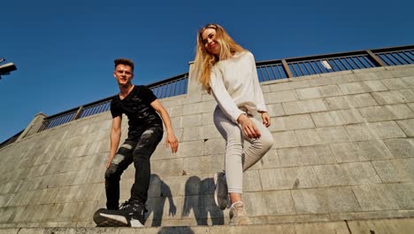 modern dancers in the street. urban lifestyle. hip-hop generation. boy's and girl's emotional moves on the video. young couple at stone wall background is looking into the camera.