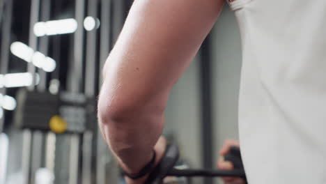gym lover arm pulling chest press handle on weight machine, muscles flexing under sleeveless shirt as he engages resistance for intense strength workout with focused effort and dynamic motion