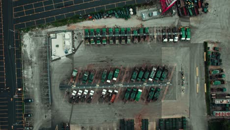 top down aerial of green garbage vehicles that carries municipal waste and trash in america