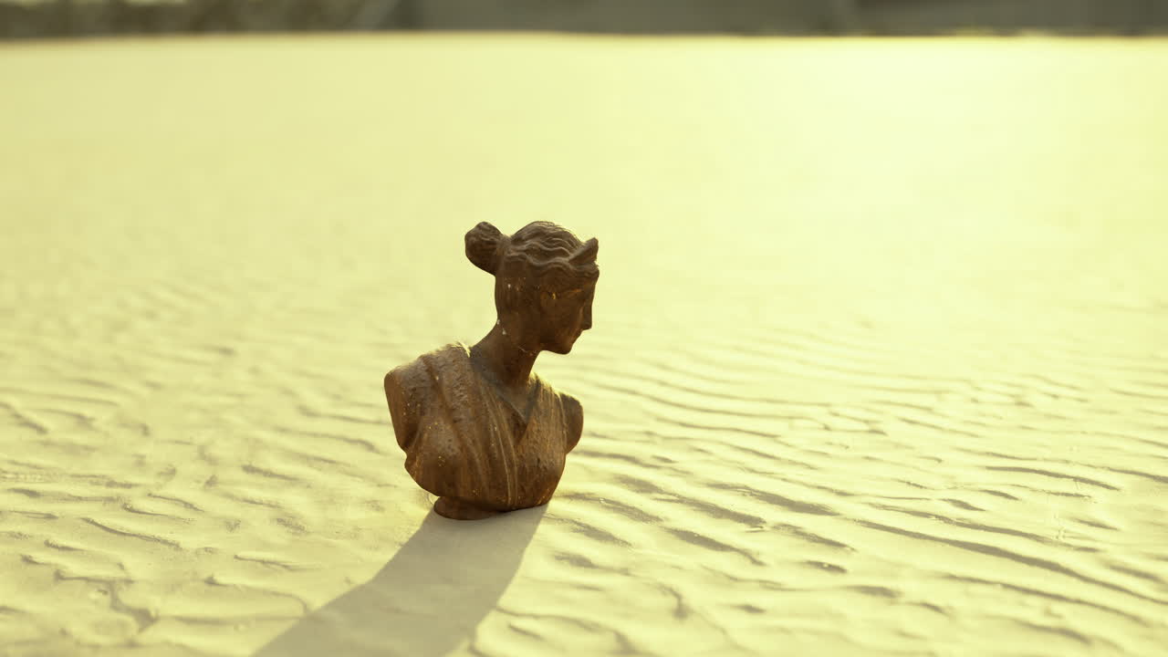 Sculpture bust on sandy terrain under golden sunlight at dusk