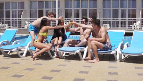 group of beautiful young people drinking cocktails and having fun at the swimming pool. slow motion shot