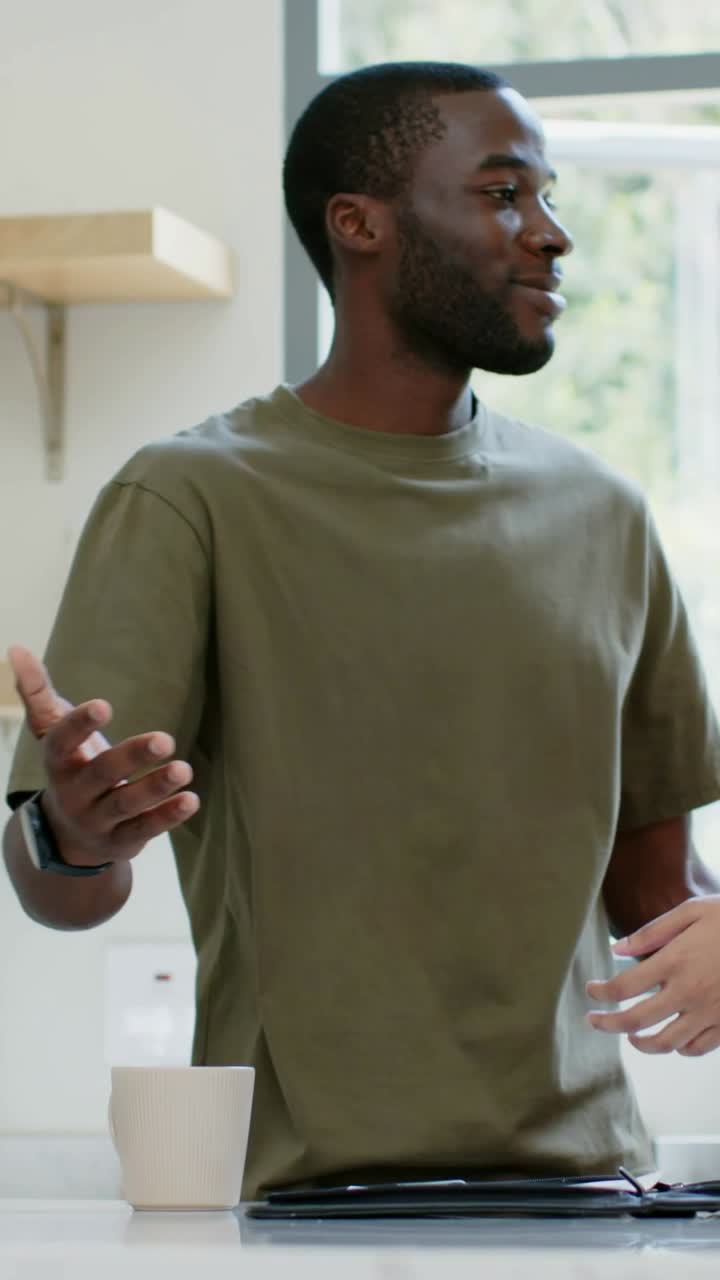 Vidéo verticale : On voit une femme entrer par la droite, un homme en t-shirt arrête sa tablette et la serre dans ses bras dans la cuisine.