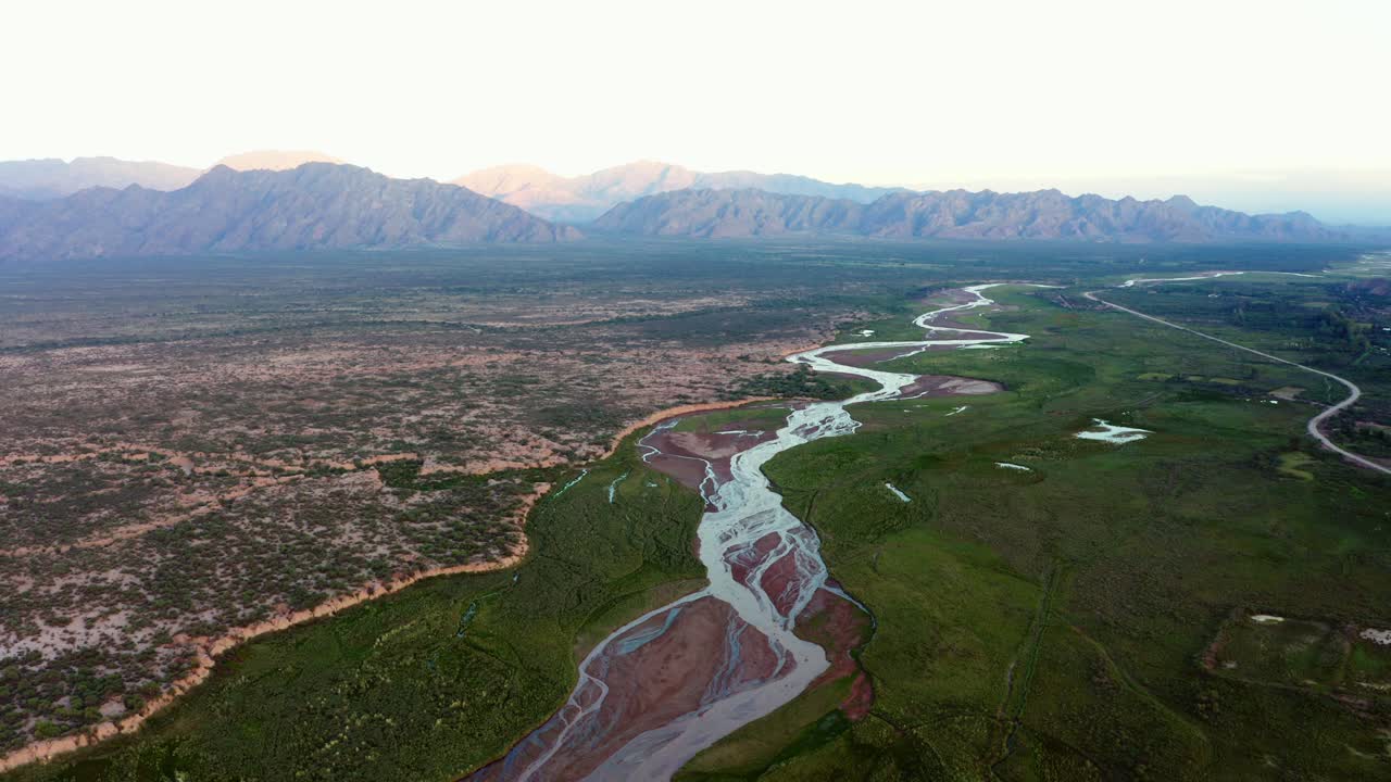 Vista aerea del corridoio fluviale verde che si snoda attraverso la valle di Fiambalá, circondata da un terreno arido