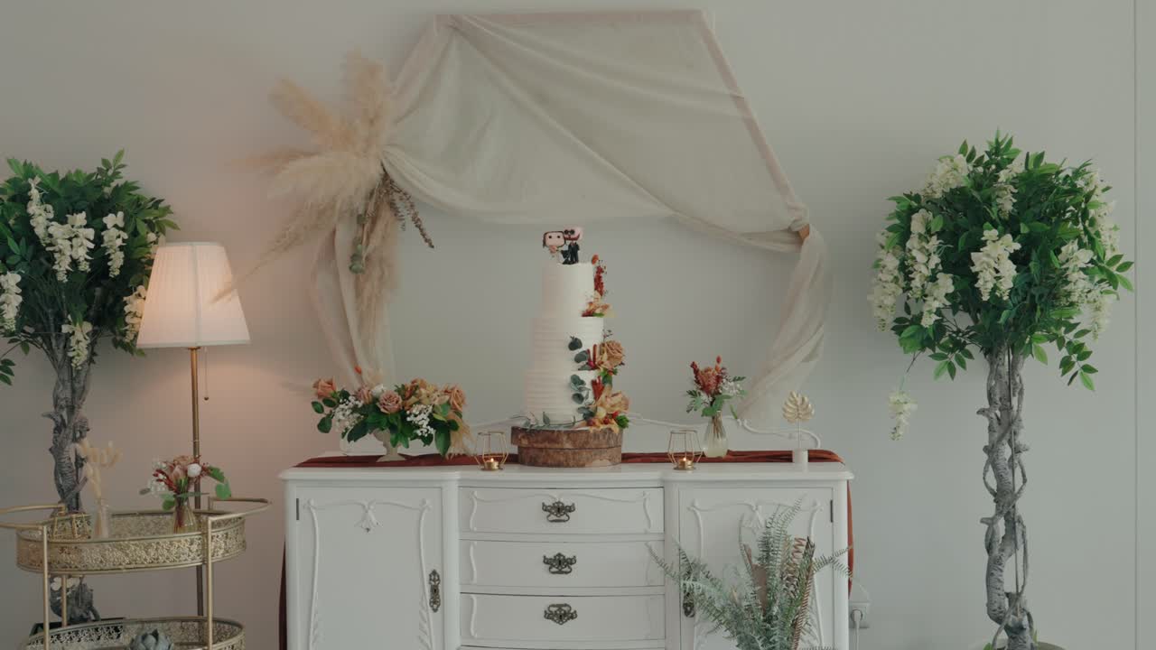 elegant wedding cake on vintage white dresser surrounded by flowers and soft decor