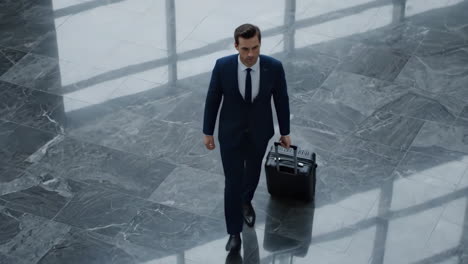 businessman walking with luggage in a modern building