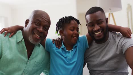 Portrait-of-african-american-grandfather,-father-and-son-smiling-together-at-home